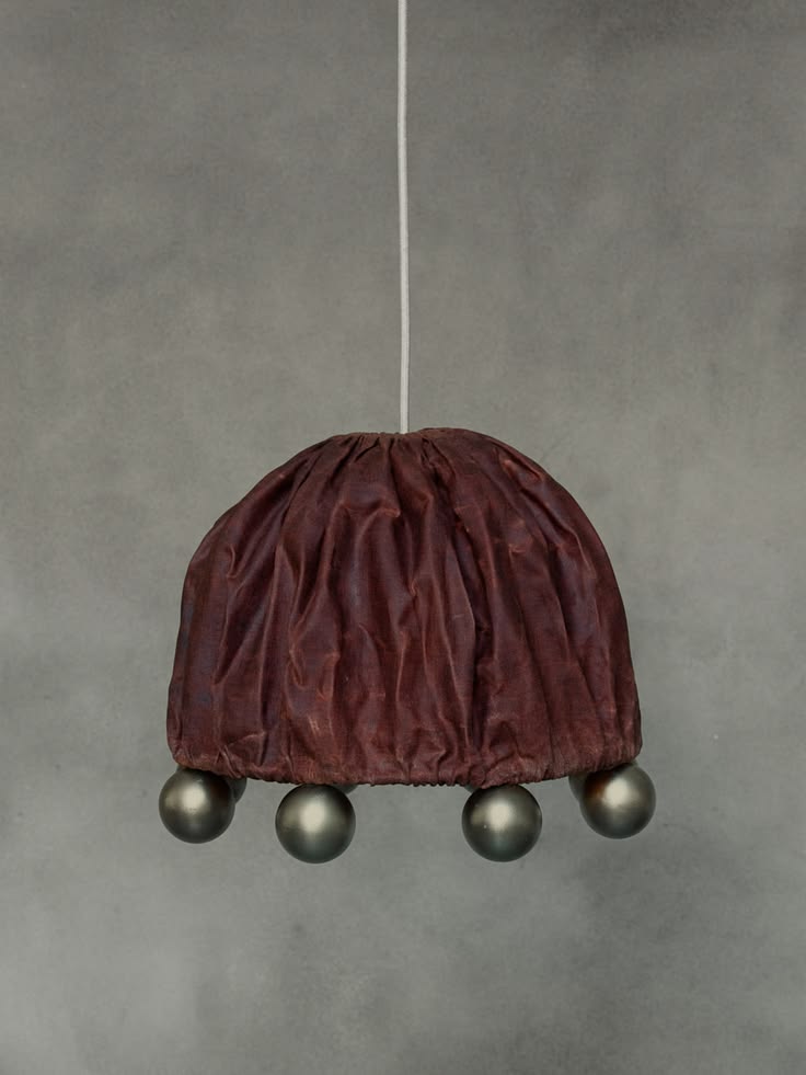 Draped fabric pendant light in deep burgundy with dark spherical feet