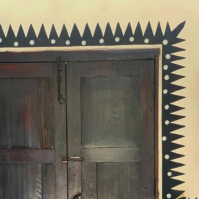 Hand-painted black sawtooth border with white dots framing a wooden doorway