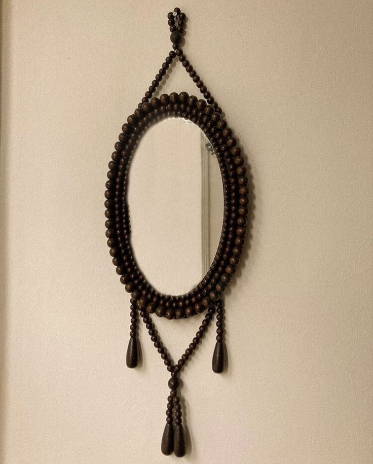 Oval mirror framed in wooden beads with tasseled drops
