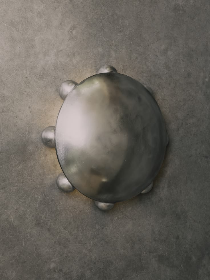 Round textured aluminum wall sconce with small ball feet