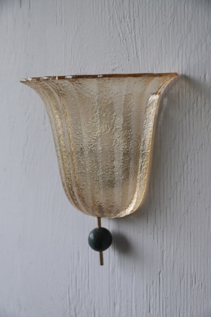 Fluted amber glass wall sconce with a dark green ball pull