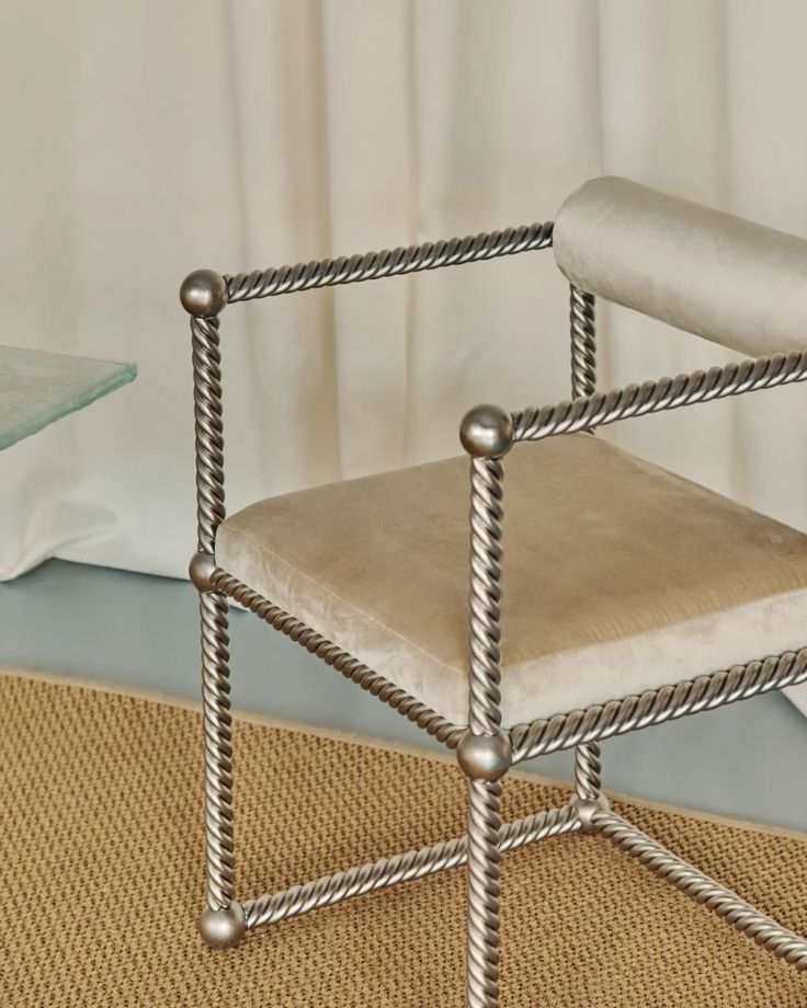Detail of a twisted rope-metal armchair with a cream velvet seat