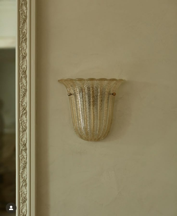 Fluted amber Murano glass wall sconce beside an ornate mirror